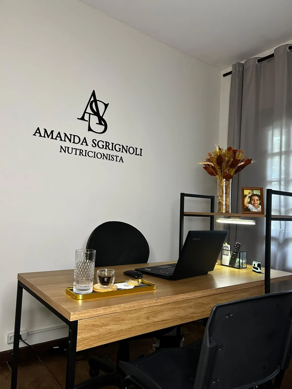 Mesa de atendimento do consultório, com o logotipo Amanda Sgrignoli Nutricionista aplicado na parede